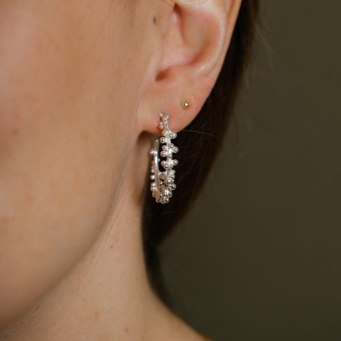 Silver granulated hoop earrings being worn
